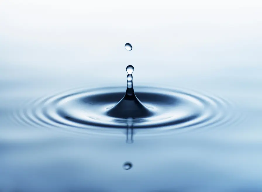 Water droplet on body of water showing ripples